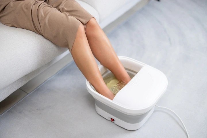 Chodidla ponořená do přístroje na koupel nohou.