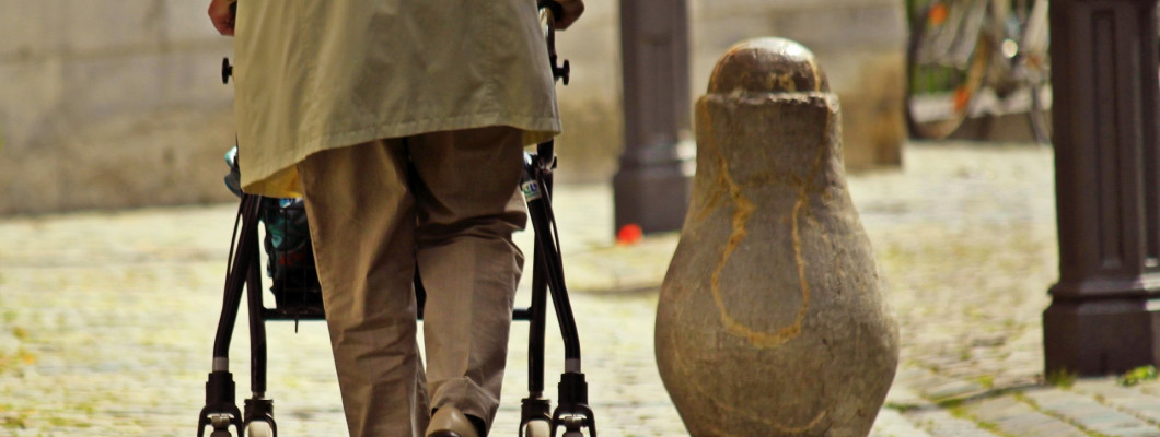 Starší muž při chůzi se 4-kolovým chodítkem.